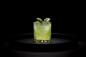 Green cocktail on round dark tray