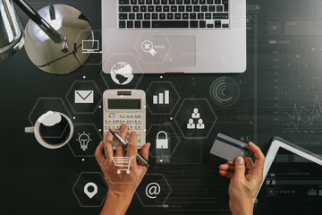 Internet shopping concept.Top view of hands working with calculator and laptop and credit card and tablet computer on dark wooden table background with Vr diagram