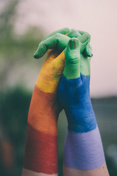 Close up of hands painted in pride rainbow