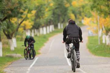 a bicyclist in a black suit is riding along the road