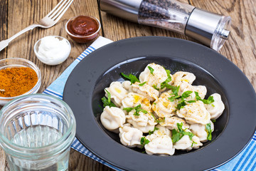 Black plate with boiled vegetarian vegetable dumplings