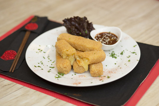 Plato blanco con bastones de muzzarella con aderezo con decoraci&oacute;n china