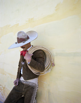 Mexican Cowboy leaning on wall with lasso.