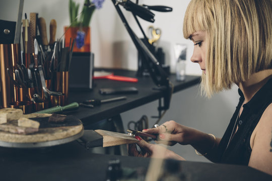 Young attractive jewelry designer working on a piece in her workshop