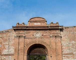Fototapeta premium Ancient gate entrance and city walls to the historic city of Siena, Tuscany, Italy