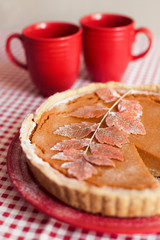 Traditional homemade pumpkin pie for thanksgiving day with two red cups