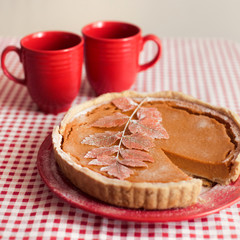 Traditional homemade pumpkin pie for thanksgiving day with two red cups