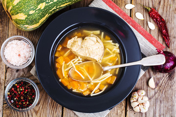 Soup with chicken, pumpkin and noodles on wooden table