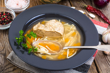 Soup with chicken, pumpkin and noodles on wooden table