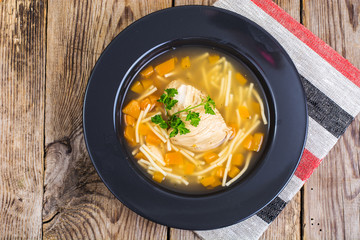 Soup with chicken, pumpkin and noodles on wooden table