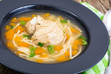 Soup with chicken, pumpkin and noodles on wooden table