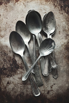 A pile of old silver spoons on grungy background