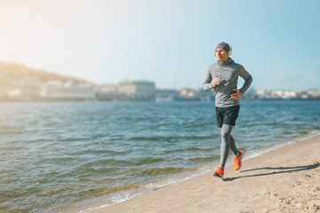 healthy lifestyle middle aged man runner running on the city beach cold season