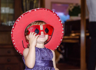 Mała dziewczynka przebiera się w duży czerwony kapelusz. Piękny uśmiech.