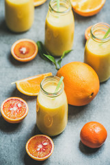 Fototapeta na wymiar Healthy yellow smoothie with citrus fruit and ginger in bottle over grey concrete background, selective focus. Clean eating, dieting, weight loss, vegetarian, vegan food concept