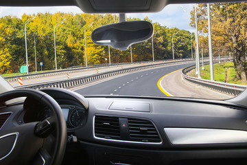 view from the car's interior to the autumn forest along the country road