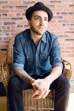 young brazillian man wearing fedora gazing outwards