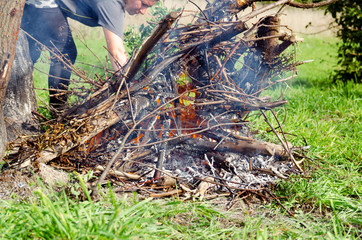 Kobieta rozpala ognisko z gałęzi drzew.