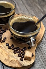 Two cups of coffee,coffee beans and brown lump sugar on wooden background.