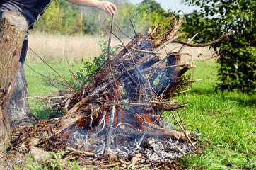 Ognisko, wypalanie gałęzi drzew na polu. - obrazy, fototapety, plakaty