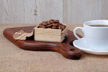 Cup of dark coffee with coffee beans on wooden cutting board . Relax time concept.