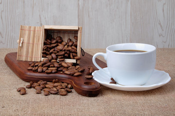 Cup of dark coffee with coffee beans on wooden cutting board . Relax time concept.