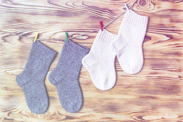 Set of cute knitted cashmere newborn baby socks  hanged on pins against wooden background