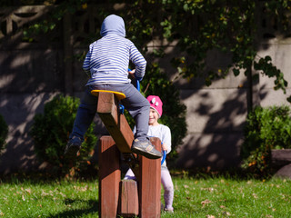 Rodzeństwo dzieci bawi się na planu zabaw w jesienny słoneczny dzień. - obrazy, fototapety, plakaty