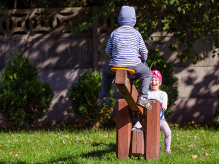 Rodzeństwo dzieci bawi się na planu zabaw w jesienny słoneczny dzień.
