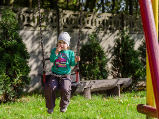 Mama huśta dziecko na huśtawce na placu zabaw w jesienny dzień. © Rajtar photography