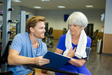 handsome young coach working out with an elderly woman