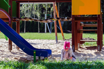 Mała dziewczynka bawi się na placu zabaw jesienią. - obrazy, fototapety, plakaty