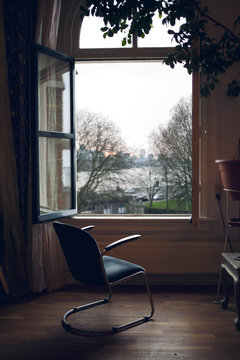 Empty chair in front of a open window with a view