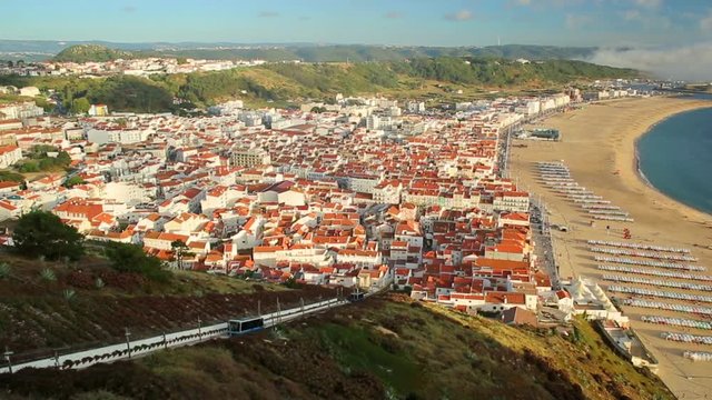 Time lapse of picturesque Nazare in Portugal by sunset light, most popular seaside resorts in Atlantic coast. Trains of Nazare Railway Funicular. Nazare Skyline and beach waterfront from Nazare Sitio.