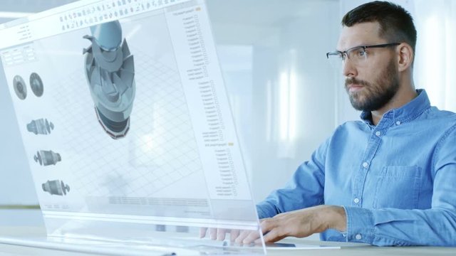 In the Near Future Professional Engineer Works on Transparent Computer Display, Constructing 3D Model of the Turbine. He Works in a Bright and Modern Office. 