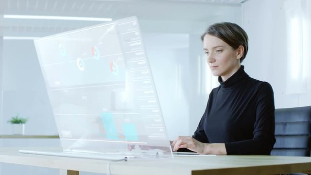 In the Near Future Renewable Energy Scientist Works with Touchscreen Transparent Computer Display. Screen Shows Interactive User Interface with Flowing Pie Charts, Graphs. 4K UHD.