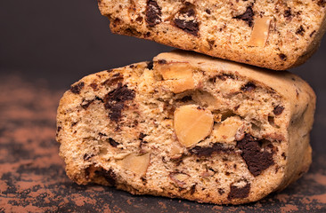 Two chocolate slice close-up of italian biscotti traditional cookies with almonds served on a black background with cocoa powder.