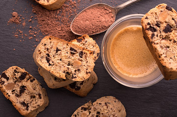 Traditional Italian cookies, biscotti and cantuccini, small pieces of sweet bread with chocolate and almonds, served with coffee on a black background.