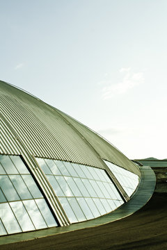 Facade of building with aluminum and glass surfaces reflecting against the sky
