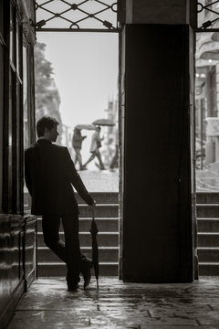 Man standing outside the rain with his umbrella.
