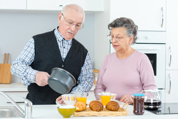 aged couple cooking and eating in the kitchen