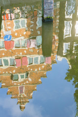 Refected architecture, Amsterdam gable facade on row houses reflections rippling in canal.