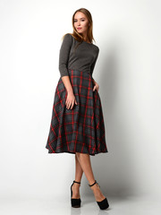 Fototapeta premium Young beautiful woman posing in new fashion plaid skirt and gray full body