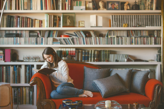 Girl reading book while sitting on sofa