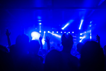 Fans raising hands at a music festival and blue concert lights