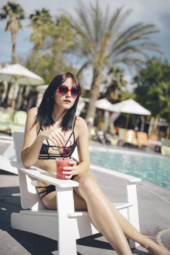 A beautiful woman having a drink by the pool