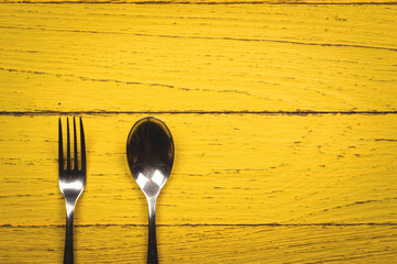 Fork and spoon on yellow Wood background, Top view with copy space.