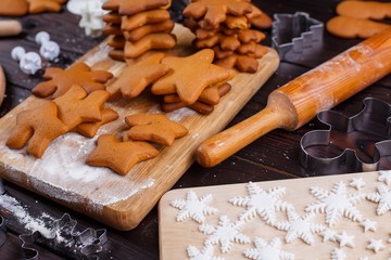 Cooking and decorating christmas gingerbread cookies. Baked cookies, mastic decorations, rolling pin and cutters on the kitchen table. Traditional festive sweets, homemade food