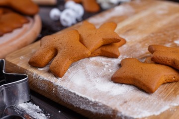 Freshly baked gingerbread on the table with flour, close up. Traditional Christmas sweets, festive food preparing