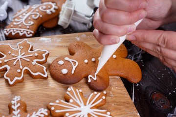 Christmas bakery. Decorating homemade gingerbread man with icing, close up. Festive culinary and New Year traditions concept